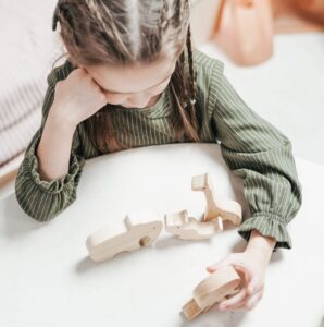 Child concentrating while playing with wooden toys during ADHD testing in New York, illustrating attention, cognitive skills, and behavioral assessment.